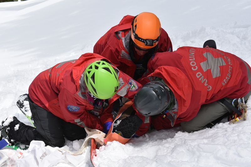 Grand County Search and Rescue team members treating a patient in deep snow